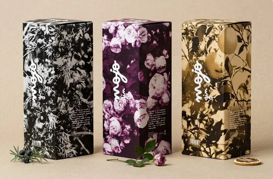 Trois étuis Mojo gin à motifs botaniques : noir et blanc, violet et doré.